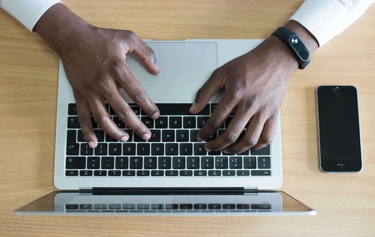 Business owner using a laptop and phone to manage a professional online presence in Kenya